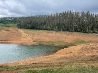Towering mountains, river with visible small island, blue and white sky, reflection visible in water, nature's gift of greenery everywhere is the way