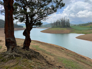 Towering mountains, river with visible small island, blue and white sky, reflection visible in water, nature's gift of greenery everywhere is the way