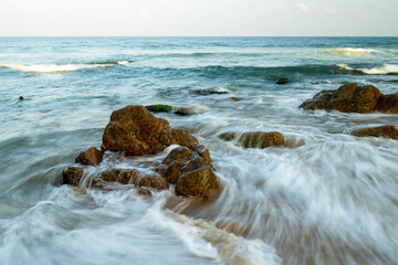Long exposure photo of waves and rocks on an overcast day.