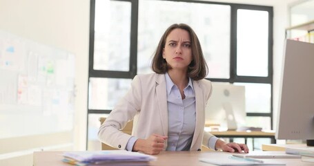 Frustrated angry aggressive business woman boss sitting at the table and looking at camera