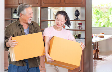 Moving day concepts, Young Asian daughter and senior father carrying boxes into a new home