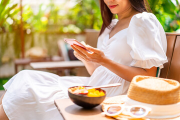 Young woman traveller relaxing and using mobile phone at tropical resort on summer vacation