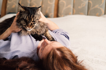 A serene moment as a woman lies down with her cat, a connection and comfort between human and pet.