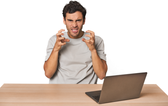 Hispanic young man working on laptop upset screaming with tense hands.