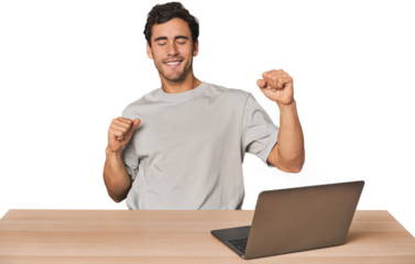 Hispanic young man working on laptop celebrating a special day, jumps and raise arms with energy.