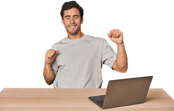 Hispanic young man working on laptop celebrating a special day, jumps and raise arms with energy. - Powered by Adobe
