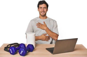 Hispanic trainer planning workout laughs happily and has fun keeping hands on stomach.