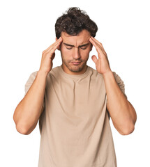 Young Hispanic man in studio touching temples and having headache.