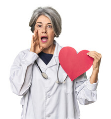 Caucasian mid-age doctor with heart symbol shouting and holding palm near opened mouth.