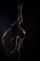 Pole dancer. Sexy girl does gymnastic exercises on pole dance. Pole dancing has become a popular...
