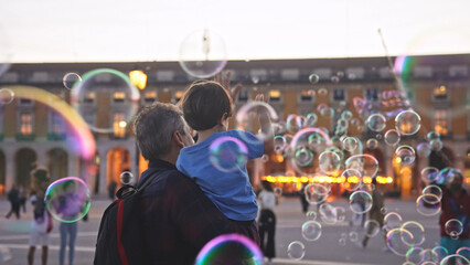 Happy childhood. Fun boy enjoy soap bubbles performance. Colorful fly show. Joyful child catch lot foam circles. Public place performer. Urban holiday square. Kid play city street. Entertainment event