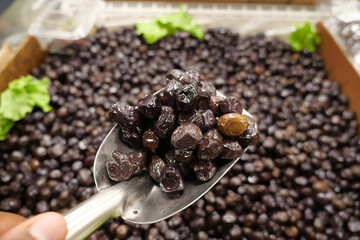slices black olives with spoon in a bowl ,