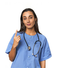 Hispanic nurse in uniform with stethoscope pointing with finger at you as if inviting come closer.