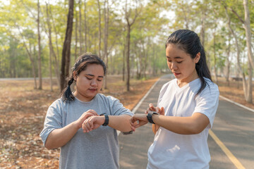 Two young female friends checking out their run time on their smart watch after their morning run...