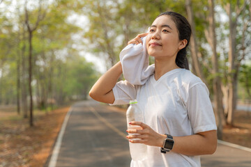 Young woman wiping off her sweat after her morning run at a local running park
