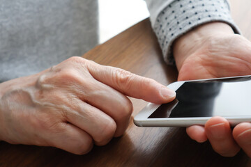 スマートフォンを操作する高齢女性の手元