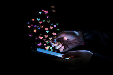 Hand with smartphone, heart icons floating out, concept of online love