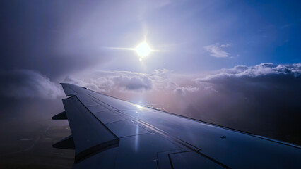 airplane flying above the clouds and sun is shinning. 