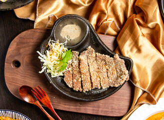 Fried pork ribs with salad, fork and spoon served in dish isolated on wooden board top view of...