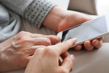Obraz premium スマートフォンの操作を教わる高齢女性の手元