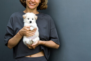 Portrait of a girl with a puppy, a woman of European appearance with curly hair holds a cute white...