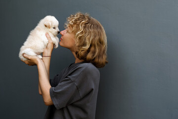 Portrait of a girl with a puppy, a woman of European appearance with curly hair holds a cute white...