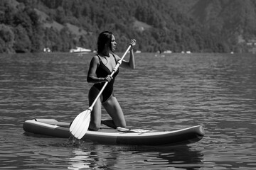 Sexy woman paddling on paddleboard. Healthy summer lifestyle. Summer sport. SUP surfing tour in adventure summer vacation. Female fit model swimming with paddle board.