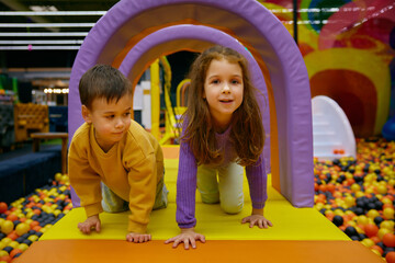 Little brother and sister positive children playing in indoor park