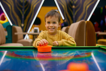 Little boy child playing air hockey at entertainment center