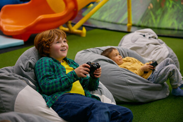 Portrait of happy boy child playing video game in kids center