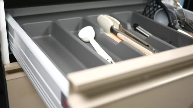 hand putting cutlery in a drawer 
