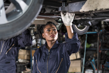 Black auto mechanic woman fixing car in auto repair  garage