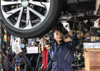 Black car mechanic woman fixing car in auto repair service shop