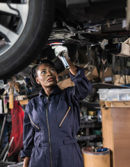 Black auto mechanic woman fixing car in auto repair  garage