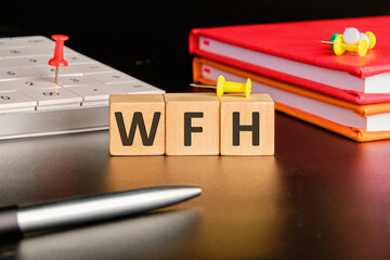 Work From Home. New business concept. Letters WFH on wooden cubes on a black background in a...