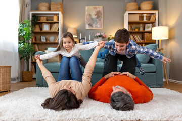 Happy family with two kids playing at home. Family sitting on floor and playing together. Parents...