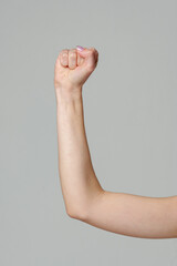 Female hand with clenched fist on gray background