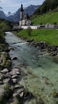 Bavarian Ramsau Berchtesgaden view along a church and icy cold mountain river with the Watzmann mountain chain at the background