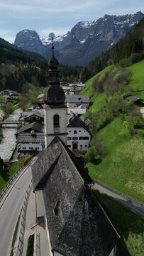 Bavarian Ramsau Berchtesgaden view along a church and icy cold mountain river with the Watzmann mountain chain at the background