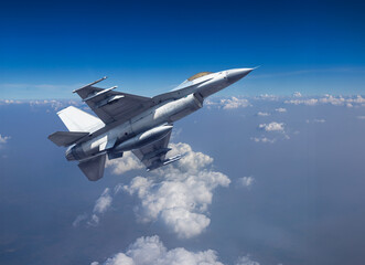 Fighter jet military aircraft flying with high speed over altocumulus cloud with blue sky 
