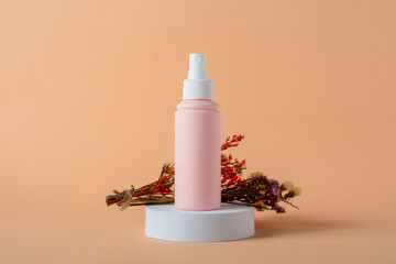 Cosmetic pink bottle, bottle, lotion or serum and dried flowers on cream background. 