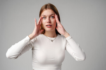 Young Woman Expressing Surprise or Confusion Against a Grey Background