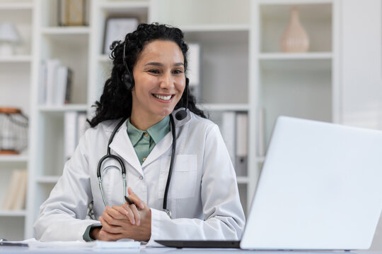 Smiling female doctor wearing a headset for an online consultation in a bright medical office. She embodies professionalism and approachability.