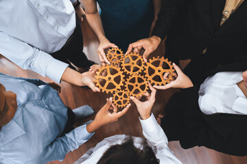 Office worker holding cog wheel as unity and teamwork in corporate workplace concept. Diverse...