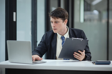 Professional business man trader using laptop computer sitting at office desk in modern office.