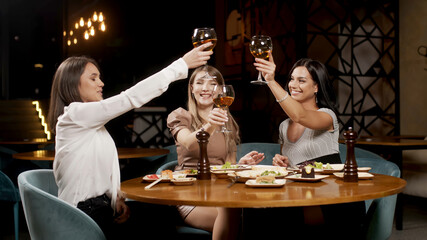 A group of beautiful women talking and having fun together in a restaurant in the evening. A group of girlfriends enjoying food and having fun. Lifestyle concept with happy women on the terrace.