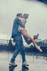 partner in love kisses a ballerina in the rain while walking around the city