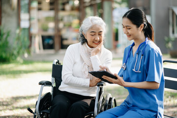 Elderly asian senior man on wheelchair with Asian careful caregiver. Nursing home hospital garden concept are walking in the garden.