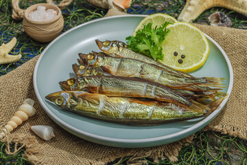 Smoked smelt with fresh lemon and herbs. Salted fish with marine decor. Trendy dish, sea rope