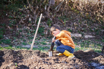 A child filling a recycling pot with soil in the vegetable garden